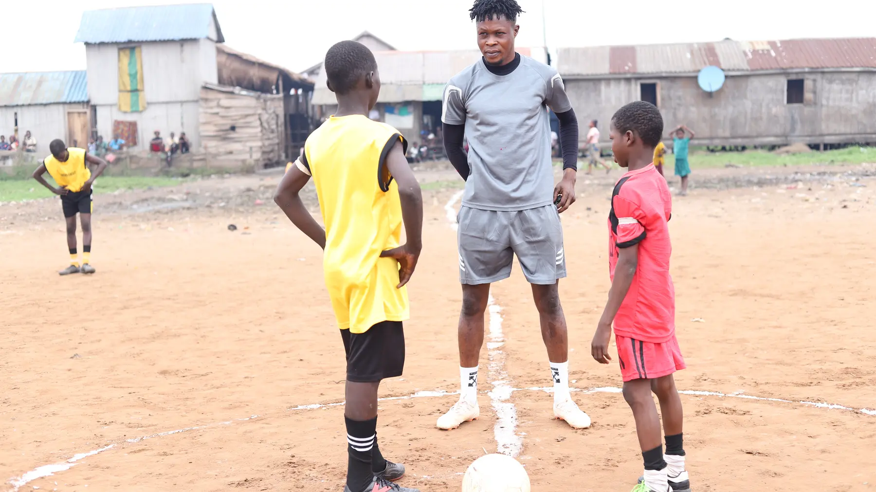 A young coach standing on the Level Up Makoko football field